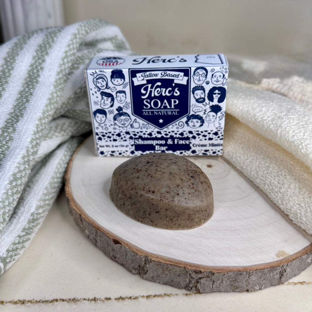 Herc's Soap shampoo and face bar on a wooden block with packaging in the background