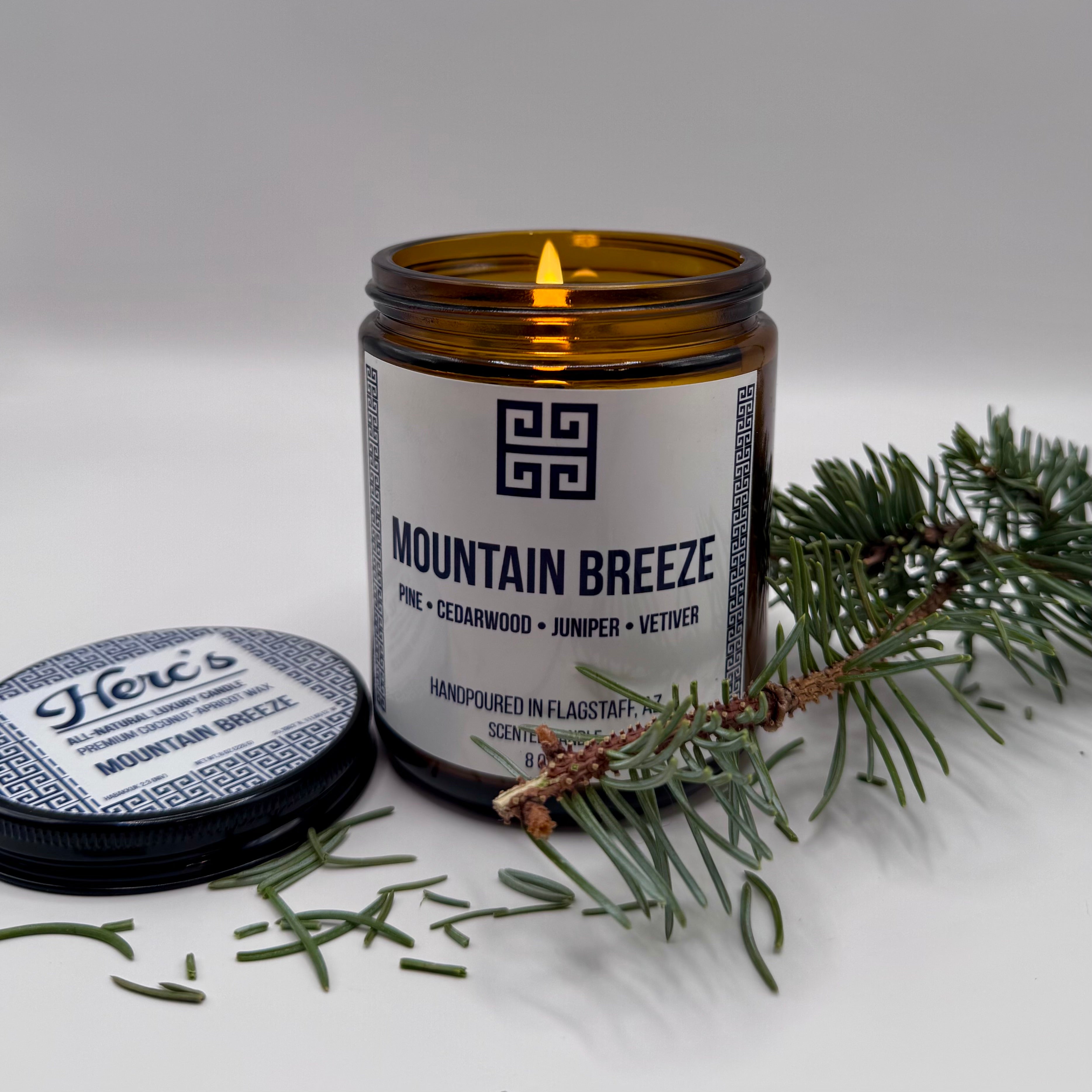 Candle labeled 'Mountain Breeze' with a branch on a white background