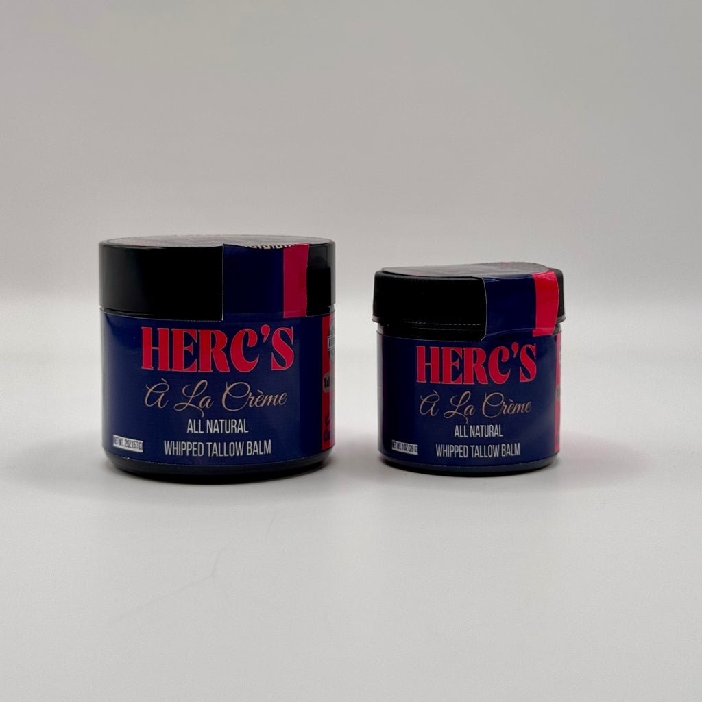 Two jars of Herc's A La Creme whipped tallow balm on a gray background