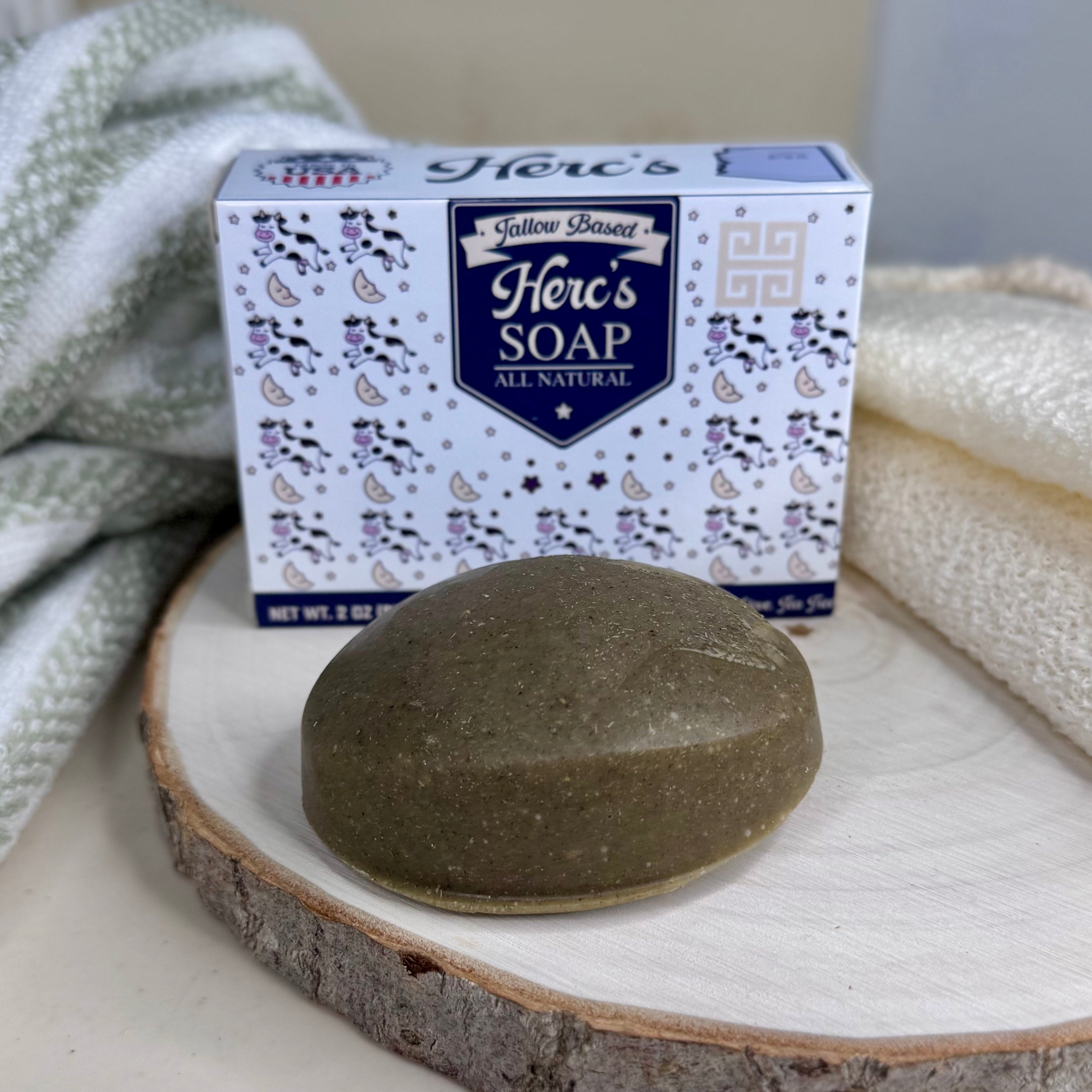 Herc's Soap bar on a wooden block with packaging in the background